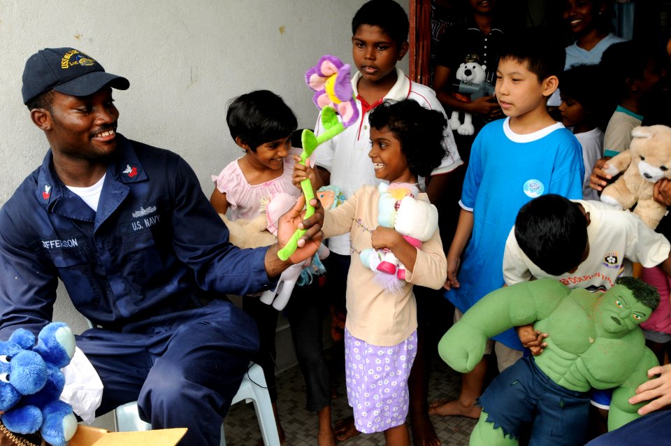 US Navy 091027-N-3830J-336 Cryptologic Technician (Technical) 1st Class Marvin Jefferson, assigned to the amphibious command ship USS Blue Ridge (LCC 19), hands out toys to children at the Praise Emmanuel Children's Home