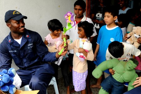 US Navy 091027-N-3830J-336 Cryptologic Technician (Technical) 1st Class Marvin Jefferson, assigned to the amphibious command ship USS Blue Ridge (LCC 19), hands out toys to children at the Praise Emmanuel Children's Home