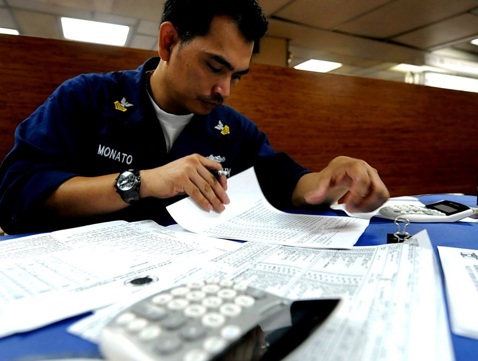 US Navy 091028-N-7280V-170 Culinary Specialist 1st Class Neil Monato verifies figures on a food preparation worksheet while underway aboard the amphibious command ship USS Blue Ridge (LCC 19)