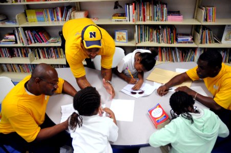 US Navy 091029-N-6220J-005 Aviation Boatswain's Mate (Fuels) 1st Class Ulric Carter, left, Boatswain's Mate 2nd Class Terrence Phillips and Operations Specialist 2nd Class Shevete Johnson help tutor students with their homework