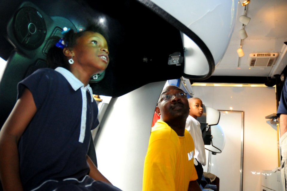 US Navy 091029-N-6220J-002 Aviation Boatswain's Mate (Fuels) 1st Class Ulric Carter watches a U.S. Navy video at the Accelerate Your Life exhibit with a young girl at the Finnigan Park Boys and Girls Club