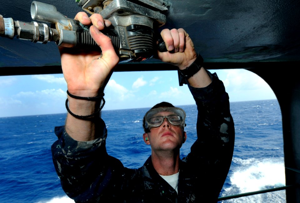 US Navy 091104-N-7280V-771 Seaman James Brown removes old paint on an overhead aboard the amphibious command ship USS Blue Ridge (LCC 19)