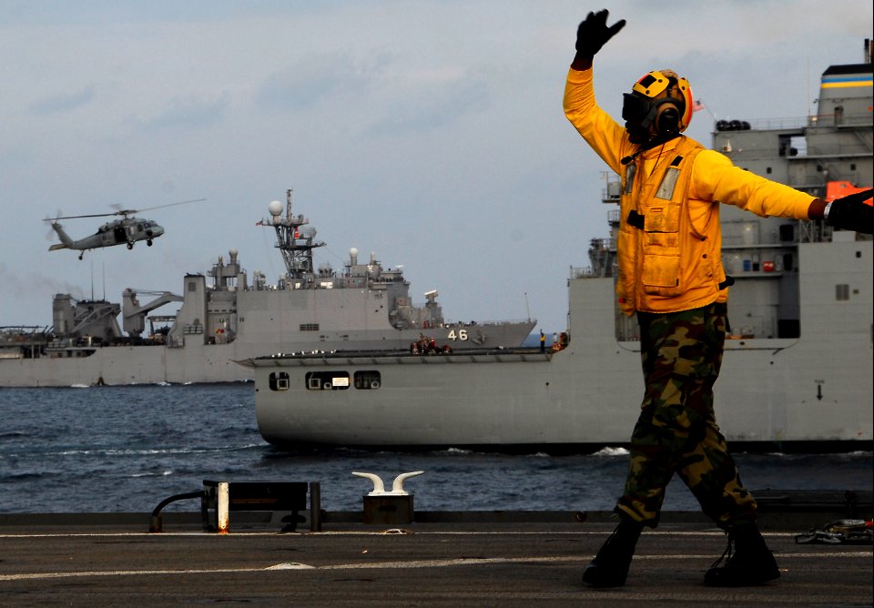 US Navy 091106-N-0807W-652 Boatswain's Mate 3rd Class Solomon Michelsignals an MH-60S Sea Hawk helicopter