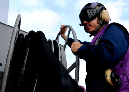 US Navy 091106-N-7478G-353 Machinist's Mate Fireman Jason VanStrander rolls up a fuel hose before flight quarters aboard the amphibious command ship USS Blue Ridge (LCC 19)