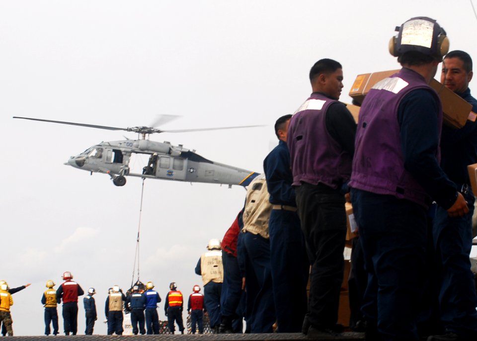 US Navy 091106-N-6692A-098 Sailors and Marines aboard the amphibious dock landing ship USS Tortuga (LSD 46) pass stores during a vertical replenishment with the Military Sealift Command dry cargo-ammunition ship USNS Alan Shepa