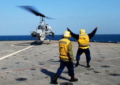 US Navy 091105-N-6692A-066 Boatswain's Mate Seaman Alfred Edwards signals a Marine Corps AH-1W Cobra helicopter