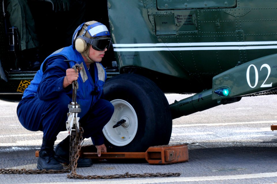 US Navy 091106-N-7478G-354 Seaman Matthew Clinton waits for the signal from the landing signal enlisted to remove the chock from an SH-60F Sea Hawk helicopter