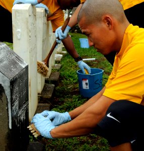 US Navy 091109-N-7498L-085 Operations Specialist 2nd Class Kristopher Wee, assigned to the guided-missile destroyer USS Chafee (DDG 90), brushes a Navy headstone during a cemetery clean in preparation for Veteran's Day
