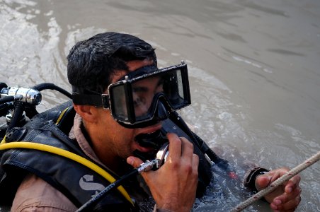 US Navy 091114-N-4154B-032 Navy Diver 2nd Class Alfred Pintor emerges from the water to communicate with his teammates during diving operations