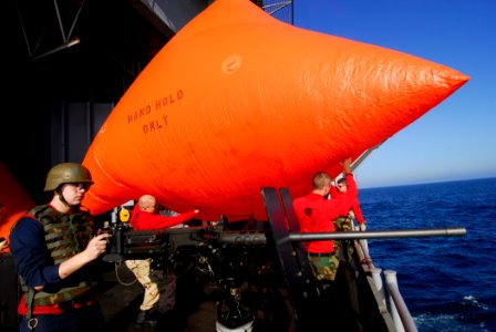 US Navy 091110-N-2475A-019 Gunner's Mate 3rd Class David Jones, left, from North Pole, Alaska, mans a .50-caliber machine gun while Aviation Ordnancemen throw an SUW-17