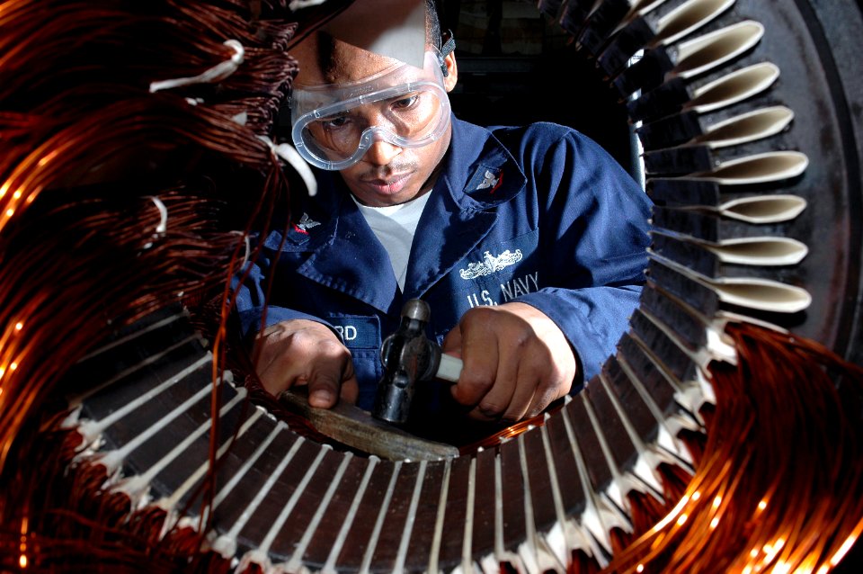 US Navy 091109-N-8960W-047 Electrician's Mate 3rd Class Tyreek Hayward lays coil to rewind a motor in the machine shop aboard the aircraft carrier USS Nimitz (CVN 68)