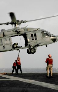 US Navy 091111-N-3595W-097 Aviation Ordnancemen hook securing lines onto an MH-60S Sea Hawk helicopter during a weapons onload