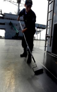 US Navy 091116-N-7280V-081 Seaman Blaine Matteson paints the main deck aboard the amphibious command ship USS Blue Ridge (LCC 19) while the ship is in Okinawa