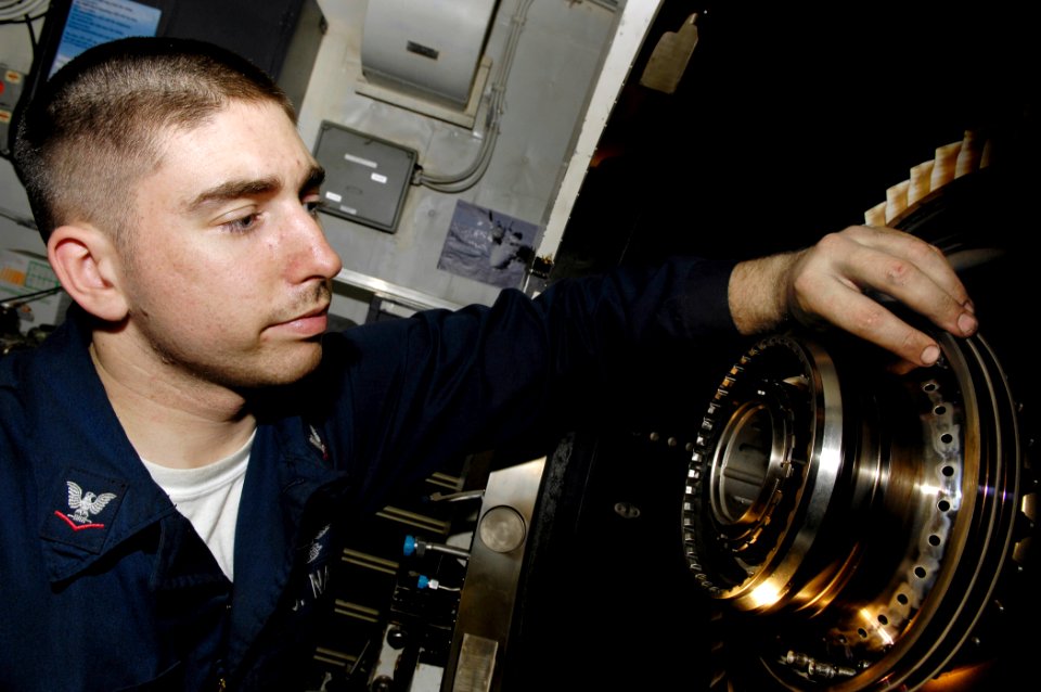 US Navy 091115-N-4954I-042 Aviation Machinist's Mate 3rd Class Ronald Melanson, screws retaining nuts onto a rotor disk attached to a high-powered turbo shaft in the jet shop