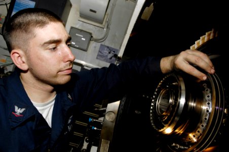 US Navy 091115-N-4954I-042 Aviation Machinist's Mate 3rd Class Ronald Melanson, screws retaining nuts onto a rotor disk attached to a high-powered turbo shaft in the jet shop