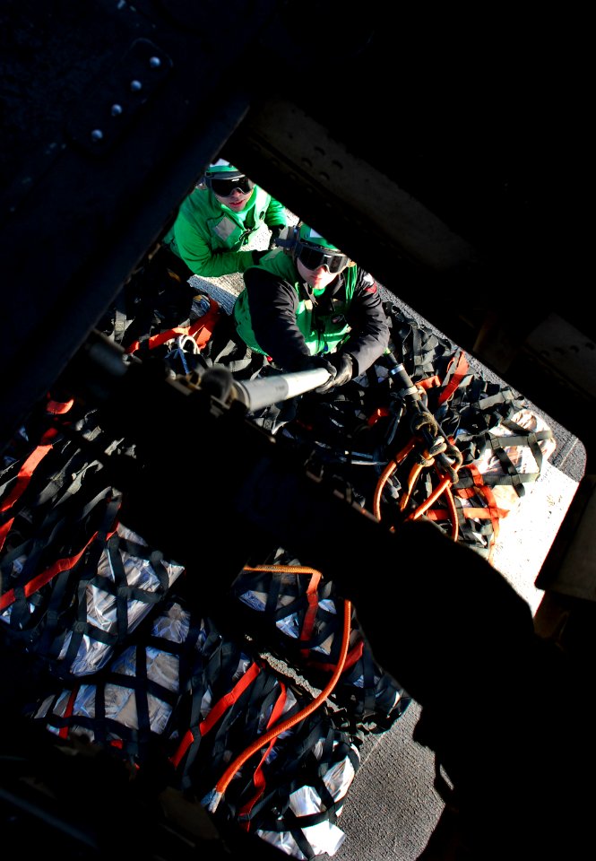 US Navy 091114-N-2475A-294 Logistics Specialist 3rd Class Paul Scott and Logistics Specialist 3rd Class Christopher Duane hook cargo onto an MH-60S Sea Hawk helicopter