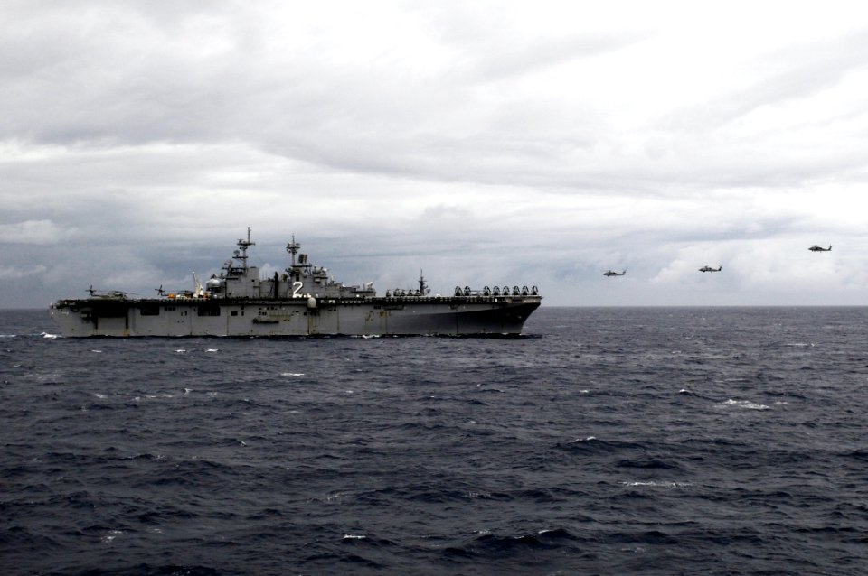 US Navy 091117-N-7280V-299 Helicopters fly above the amphibious assault ship USS Essex (LHD 2) as it maneuvers into formation during Annual Exercise (ANNUALEX 21G)