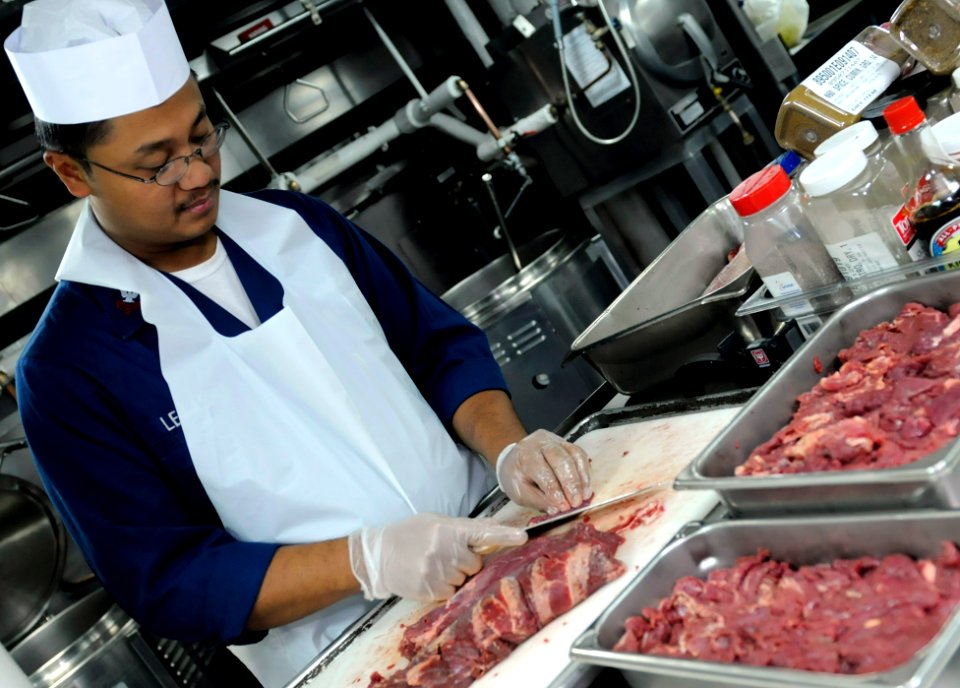 US Navy 091118-N-7478G-162 Culinary Specialist 1st Class Jeffrey Legaspi cuts beef for a Mongolian barbeque meal in the wardroom