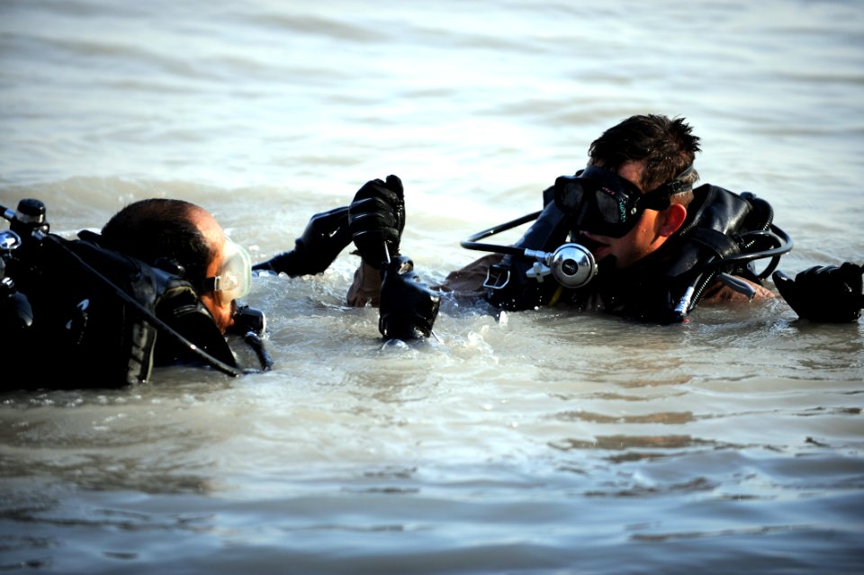 US Navy 091116-N-4154B-105 Navy Diver 2nd Class Zachery Dojaquez and an Iraqi Navy diver work together to run lifting wires from a crane to a sunken barge during dive operations