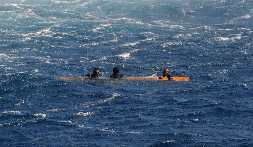 US Navy 091117-N-9500T-177 Three men cling to a piece of wood just before they are rescued by a boat crew from USS Chosin (CG 65)