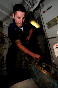 US Navy 091123-N-3038W-010 Machinist's Mate 3rd Class Derek Lipchey lowers a check valve to spaces below aboard USS Nimitz (CVN 68) photo