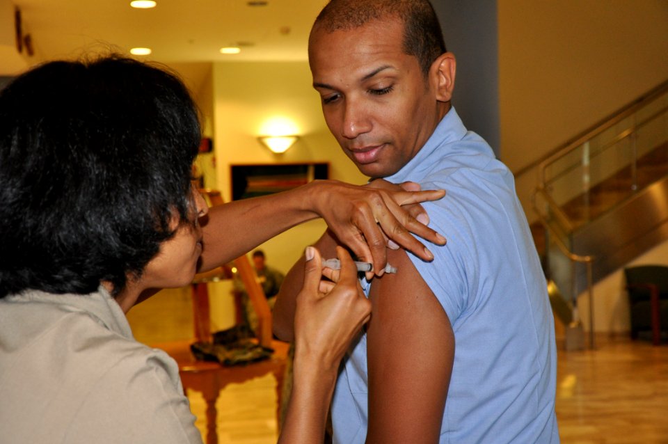US Navy 091119-N-1825E-253 Mass Communication Specialist 1st Class Paul Cage, leading petty officer of the Naval Station Rota public affairs office, right, receives the H1N1 vaccine during base-wide immunizations