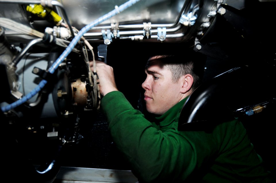 US Navy 091119-N-3038W-097 Aviation Machinist's Mate 2nd Class Joseph Parry, assigned to the Black Ravens of Tactical Electronic Attack Squadron (VAQ) 135, performs maintenance on a jet engine aboard the aircraft carrier USS Ni