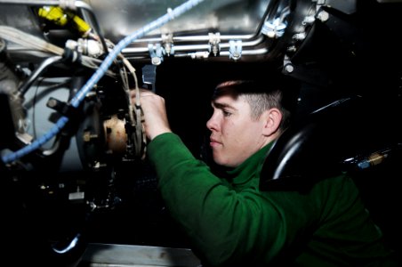 US Navy 091119-N-3038W-097 Aviation Machinist's Mate 2nd Class Joseph Parry, assigned to the Black Ravens of Tactical Electronic Attack Squadron (VAQ) 135, performs maintenance on a jet engine aboard the aircraft carrier USS Ni