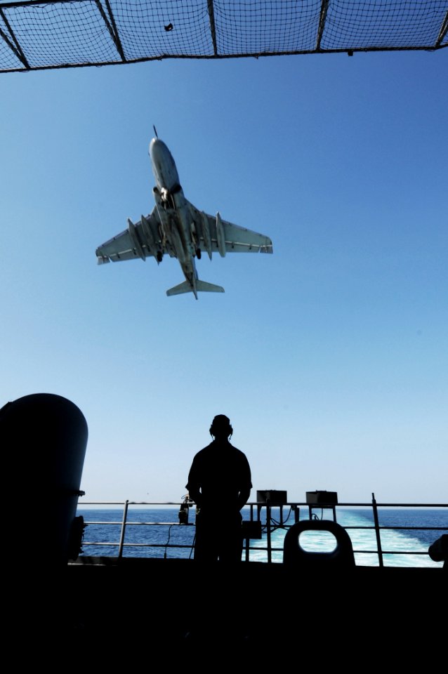 US Navy 091119-N-3038W-020 A Sailor stands aft lookout while an EA-6B Prowler assigned to the Black Ravens of Tactical Electronic Attack Squadron (VAQ) 135 approaches for landing aboard the aircraft carrier USS Nimitz (CVN 68)