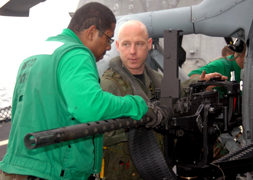 US Navy 091119-N-7058E-176 Aviation Machinist's Mate 3rd Class Joseph Williams and Aviation Warfare Systems Operator 1st Class Joseph Ward install a GAU-21 .50-caliber machine gun onto an MH-60S Sea Hawk helicopter