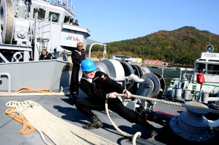 US Navy 091121-N-8335D-120 Electronics Technician 3rd Class Joshua Taylor strains on a mooring line as the mine counter-measures ship USS Defender (MCM 2) arrives in Chinhae for Exercise Clear Horizon