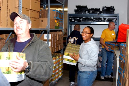 US Navy 091123-N-1580K-944 Chief Builder Dan Meddison, Logistics Specialist 2nd Class Gloria Pearson and Sailors carry boxes of canned vegetables while at the Mid Coast Hunger Prevention Program (MCHPP) storehouse