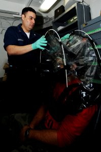 US Navy 091124-N-3038W-080 Damage Controlman 3rd Class Richard Mendoza assists Aviation Ordnanceman 2nd Class Oscar Diaz with a gas mask fitting