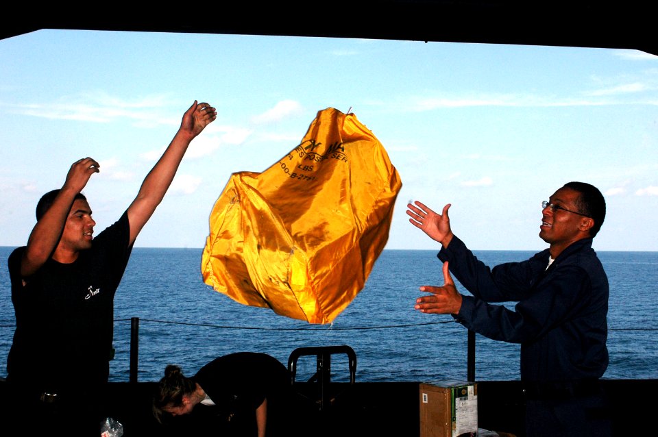 US Navy 091122-N-8960W-011 Logistics Specialist Seaman Michael Gonsalves tosses a mailbag to Logistics Specialist 3rd Class Stephen Alexander