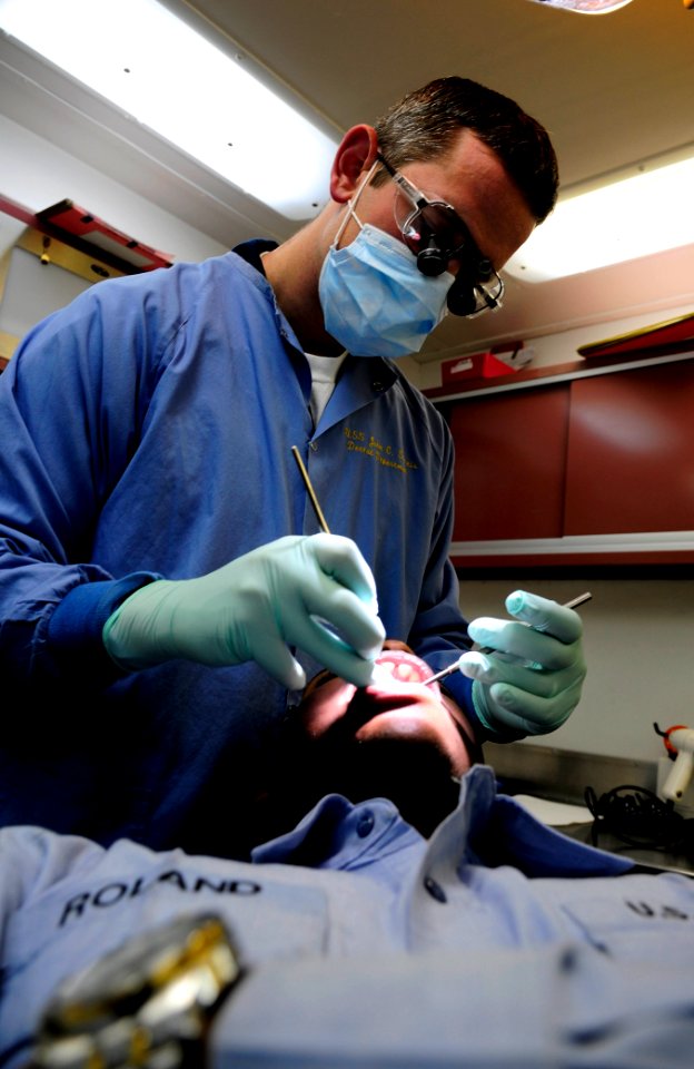 US Navy 091204-N-9928E-011 Lt. Kevin Smith, performs a dental examination on Ship's Serviceman 3rd Class Colleth Roland, in the ship's dental office aboard the aircraft carrier USS John C. Stennis (CVN 74)