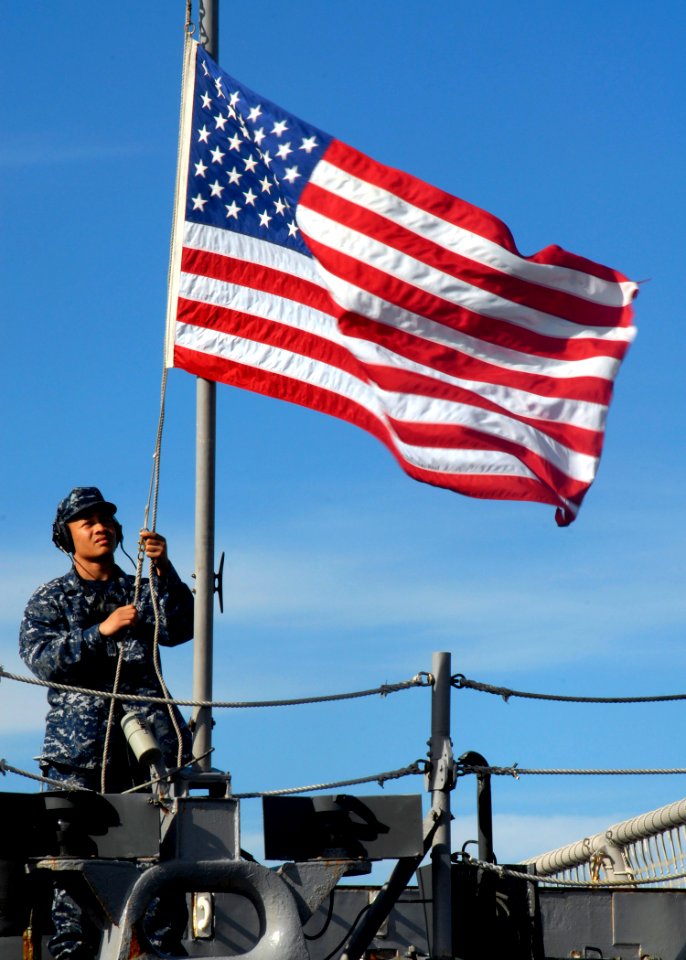 US Navy 091203-N-2456S-146 A Sailor lowers the ensign on the fantail of USS Nicholas (FFG 47)