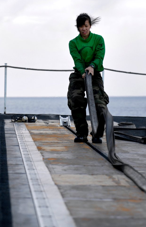 US Navy 091206-N-4954I-038 Aviation Boatswain's Mate (Equipment) 3rd Class Susan Luong, from Renton, Wash., replaces a protective rubber strip on catapult two on the flight deck of the Nimitz-class aircraft carrier USS John C