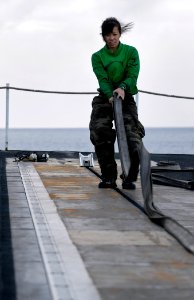 US Navy 091206-N-4954I-038 Aviation Boatswain's Mate (Equipment) 3rd Class Susan Luong, from Renton, Wash., replaces a protective rubber strip on catapult two on the flight deck of the Nimitz-class aircraft carrier USS John C