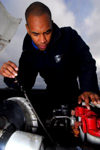 US Navy 091204-N-2475A-013 Aviation Boatswain's Mate (Handling) Airman Reshawn Orr, from Orlando, checks the oil of aircraft towing tractor on the flight deck aboard the Nimitz-class aircraft carrier USS John C. Stennis (CVN 74
