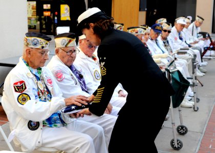 US Navy 091204-N-7032B-152 Command Master Chief Kathleen A. Hansen, assigned to Naval Medical Center San Diego, presents an American flag to retired Chief Electrician's Mate Stuart Hedley, a Pearl Harbor survivor