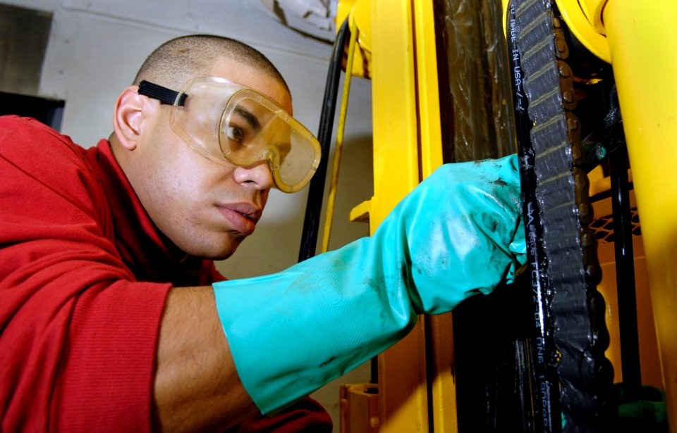 US Navy 091204-N-4954I-023 Aviation Ordnanceman 3rd Class Hector Cubero, from New York, applies grease onto a forklift chain aboard the Nimitz-class aircraft carrier USS John C. Stennis (CVN 74)