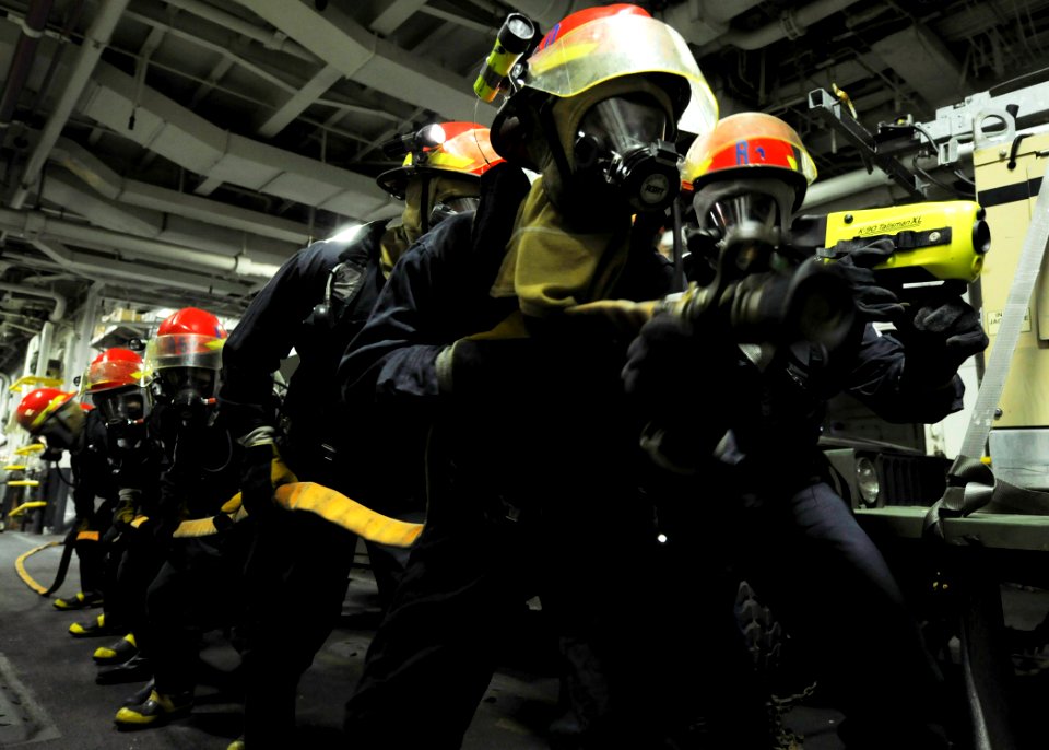 US Navy 091205-N-2735T-005 Sailors form a fire party to attack a simulated fire in the upper vehicle storage bay aboard the amphibious assault ship USS Nassau (LHA 4)