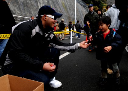 US Navy 091205-N-6233H-097 Hull Technician 3rd Class Kevan Kirksey hands a child a candy cane as he and his family walk towards the aircraft carrier USS George Washington (CVN 73)