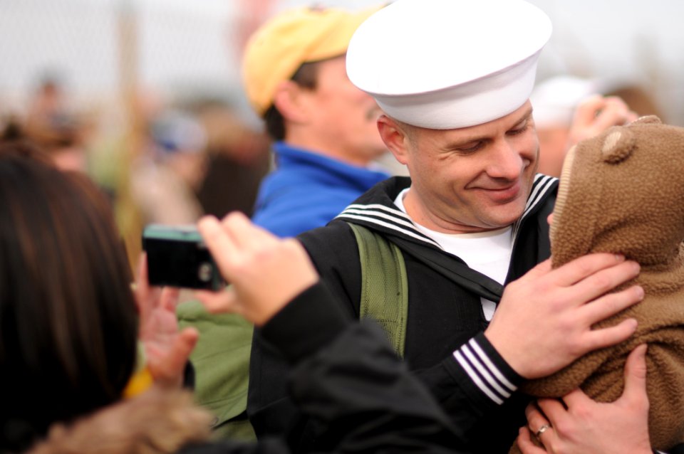 US Navy 091208-N-8907D-444 Culinary Specialist 2nd Class Timothy Faulkner holds his child for the first time during a homecoming celebration for the amphibious dock landing ship USS Fort McHenry (LSD 43)