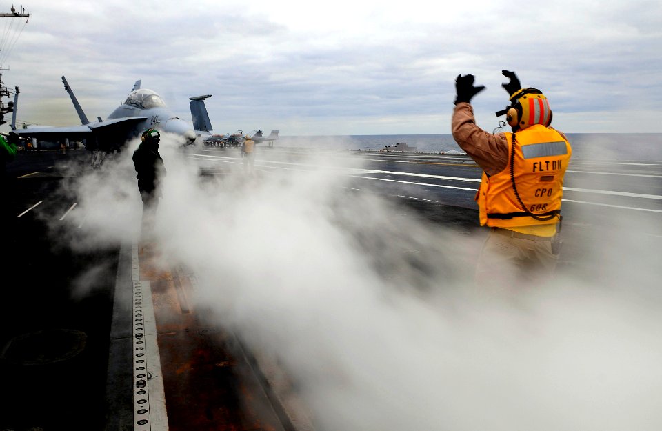 US Navy 091209-N-9928E-273 Chief Aviation Boatswain's Mate (Handling) Victor Cadena, from Los Angeles, directs an F-A-18C Hornet