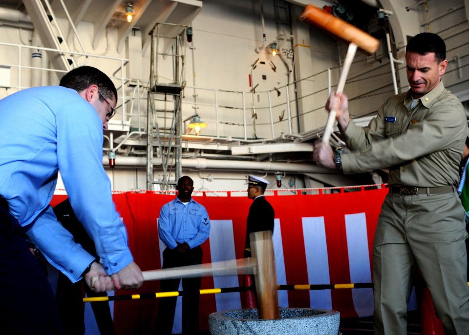 US Navy 091214-N-0120A-089 Lt. Cmdr. David Waner and Information Specialist 3rd Class Joseph Hyde pound mochi during a ceremony aboard USS Essex (LHD 2)