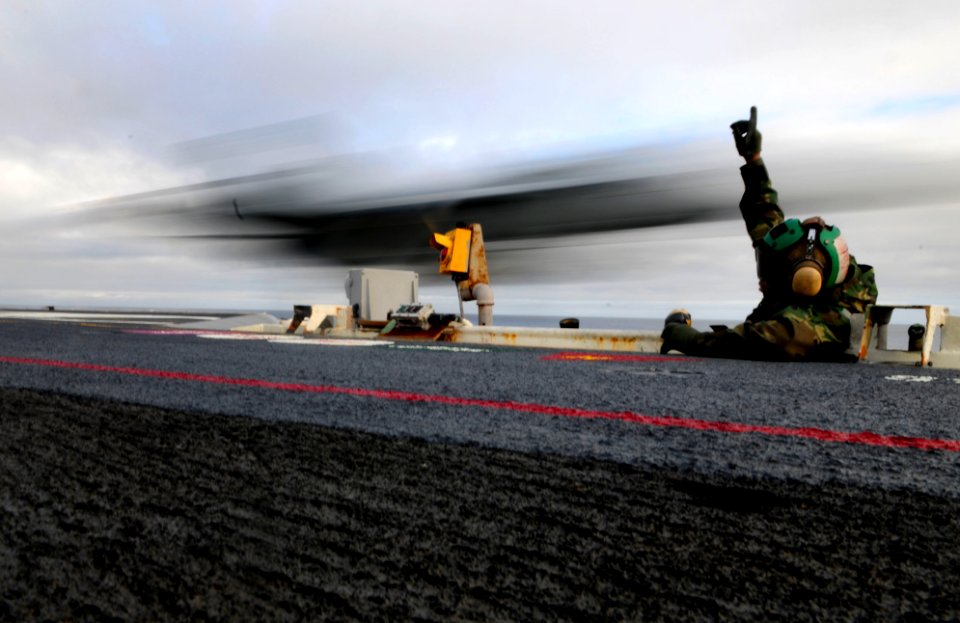 US Navy 091211-N-9928E-095 Aviation Boatswain's Mate (Equipment) Airman William Buck, from Virginia Beach, Va., mans the bow safety watch as an F-A-18 Hornet launches from the Nimitz-class aircraft carrier USS John C. Stennis (