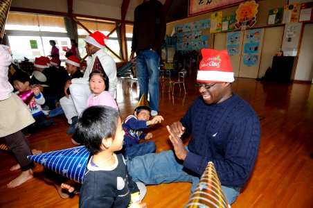 US Navy 091218-N-8335D-066 Religious Program Specialist 2nd Class Josia Onyango plays with a child during a holiday community service project at the Kusuzumi daycare center where Sailors from Fleet Activities Sasebo