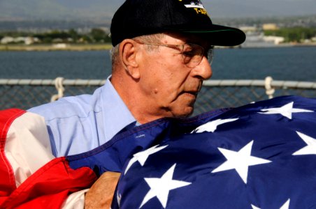 US Navy 091218-N-7498L-254 Able Bodied Seaman John Douklias gathers the national ensign aboard the Military Sealift Command combat stores ship USNS San Jose (T-AFS 7)