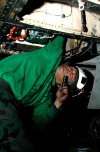US Navy 091214-N-3327M-045 Aviation Machinist's Mate 2nd Class Raynard Eugenio performs maintenance on an F-A-18C Hornet